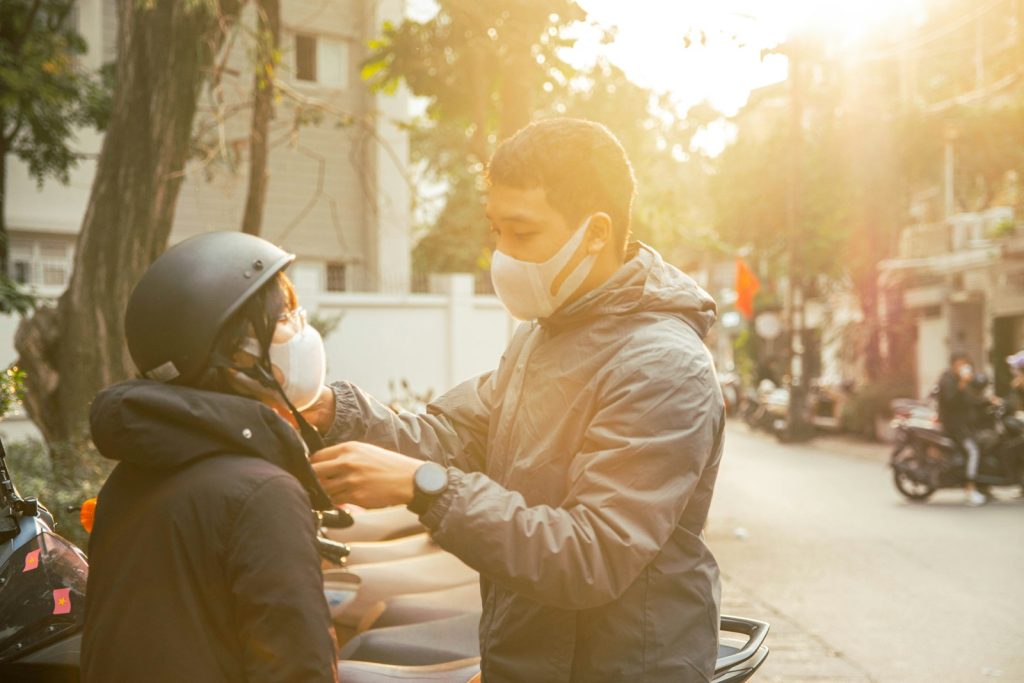 a man wearing a face mask is handing something to a child on a scoot