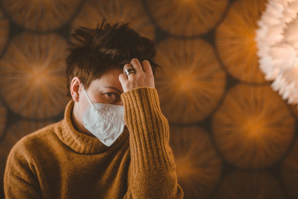 woman in brown sweater covering her face with her hand